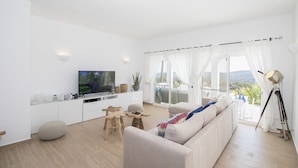 Una sala de estar moderna con un televisor de pantalla plana, un sofá, una mesa de centro y un comedor.