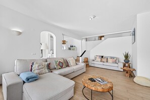 A modern living room with a sectional sofa, a coffee table, and a staircase leading to an upper level.