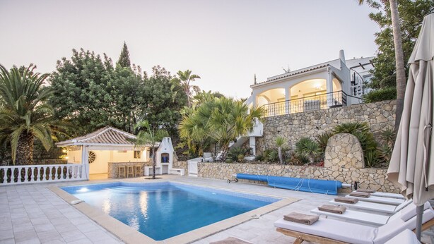 Una piscina con sillones de descanso y una pared de piedra.