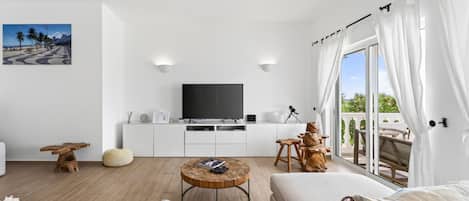 Ett modernt vardagsrum med en platt-TV, ett soffbord i trä och en soffa.