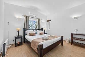 A modern hotel room with a large bed, bedside lamps, a small table, and a view of the outdoors.