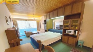 A compact room with a bed, a desk, a chair, a small table, a microwave, and a cabinet. - Studio with a view to the Tauplitzalm (Bad Mitterndorf)