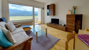 A living room with a sofa, a glass coffee table, a TV, and a wooden cabinet. - Holiday apartment in the resort Sonnenalm (Sonnenalm)