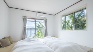 Un dormitorio con una cama grande, una ventana con cortinas y vistas a palmeras.