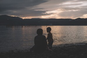 A serene lakeside scene with a person and a child by the water's edge. - Sakura Beach Garden (Hiji)