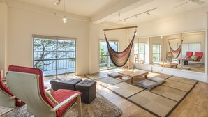 Un salón espacioso con un gran ventanal, una hamaca, un sofá y una mesa de madera.