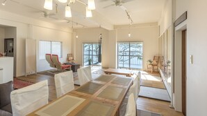Amplia sala de estar con un gran comedor, múltiples sillas, ventiladores de techo y ventanas amplias que permiten la entrada de luz natural.
