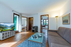 Un salon moderne avec une télévision, un canapé, une table basse et une vue sur un paysage montagneux.