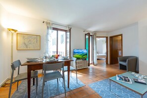 Un salon moderne comprenant un coin repas, un téléviseur et offrant une vue sur un paysage verdoyant.