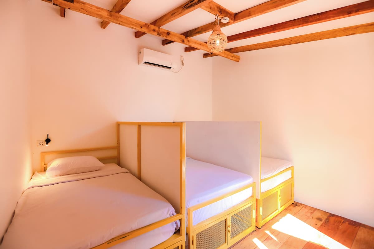 Ein Zimmer mit zwei hölzernen Etagenbetten, einem Deckenventilator und einer Klimaanlage.