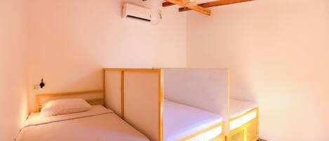 A room with two wooden bunk beds, a ceiling fan, and an air conditioning unit.