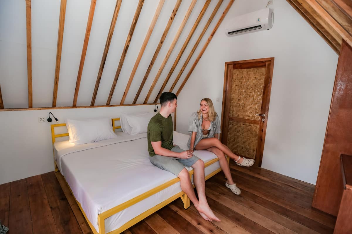 Ein Schlafzimmer mit Holzboden, einem Bett mit weißer Bettwäsche und einer Holztür.