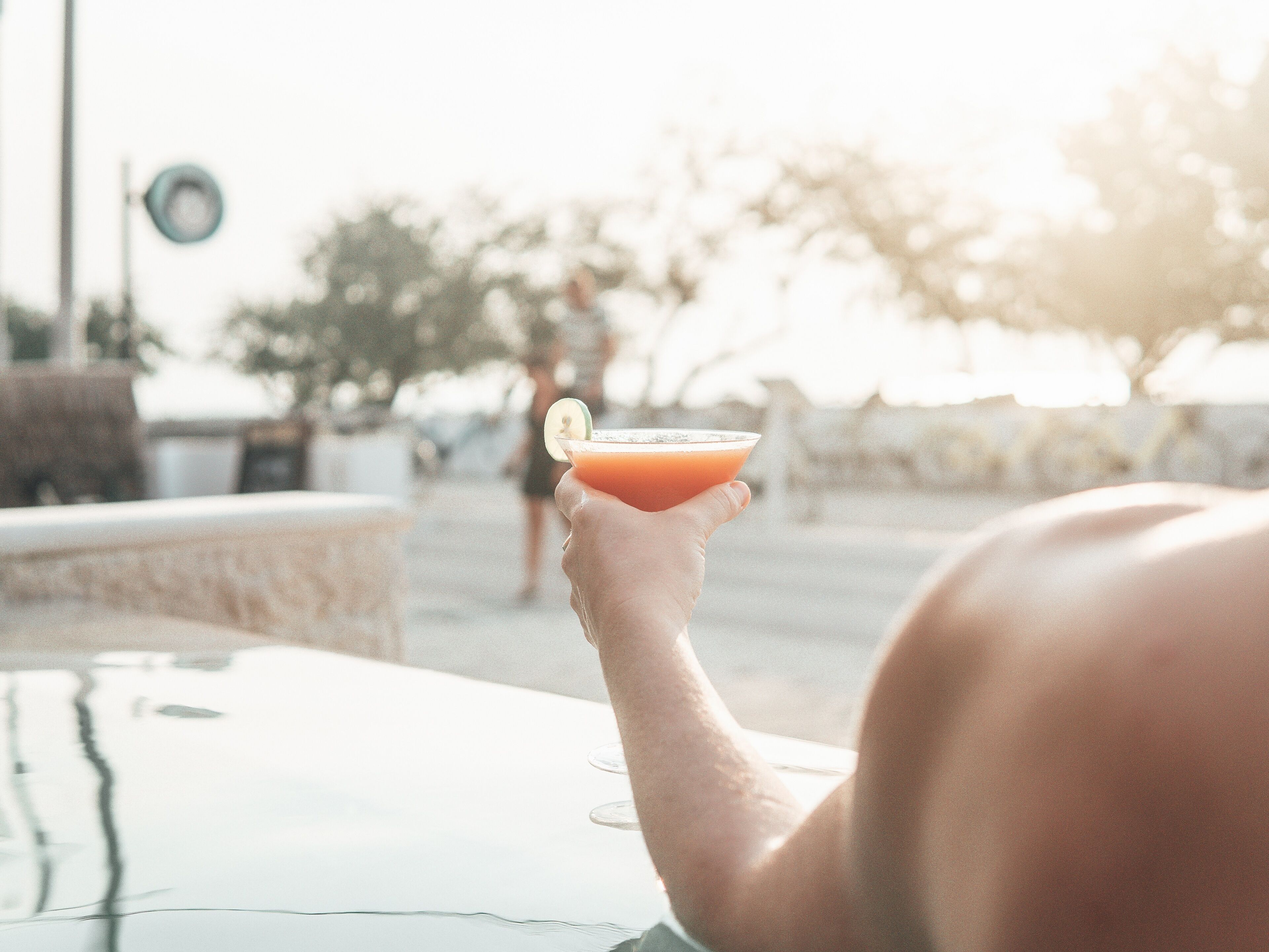 Une personne tenant un cocktail décoré d’une tranche de citron vert.