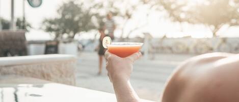 Une personne tenant un cocktail décoré d’une tranche de citron vert.