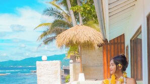 A person sitting on a beige outdoor sofa with a view of a pool and ocean. - Absolute Oceanfront 2 Bedroom Villa Nautilus (Sengkidu)