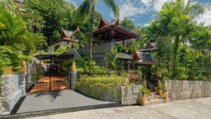A traditional Thai-style building with a gated entrance, surrounded by lush greenery and palm trees. - Classy 4-BR Seaview Villa at Surin Beach (Choeng Thale)