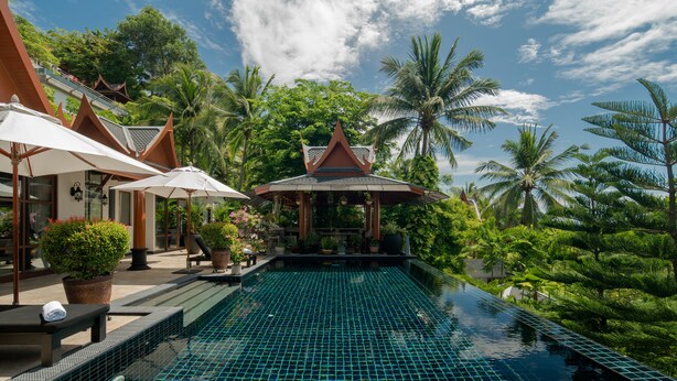 A pool area with tiled flooring, lounge chairs, umbrellas, and potted plants. - Classy 4-BR Seaview Villa at Surin Beach (Choeng Thale)