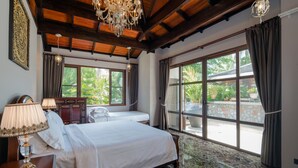 A spacious bedroom with a large bed, a wooden ceiling, and a view of the outdoors through large windows. - Classy 4-BR Seaview Villa at Surin Beach (Choeng Thale)