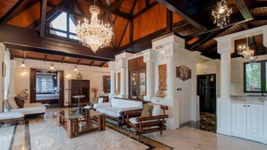 A spacious living area with a high ceiling, chandeliers, a marble floor, and a large window providing natural light. - Classy 4-BR Seaview Villa at Surin Beach (Choeng Thale)