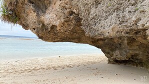 A beach with a large rock formation creating a natural arch over the sand. - Sesoko Terrace 2 (Motobu)