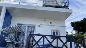 A white building with a blue door, a small window, and a balcony with a metal railing. - Sesoko Terrace 2 (Motobu)