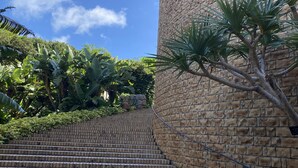 A staircase leading up to a building with a brick facade, surrounded by lush greenery. - Sesoko Terrace 2 (Motobu)