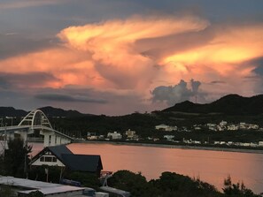 Un puente sobre un cuerpo de agua, con colinas al fondo y un cielo al atardecer.