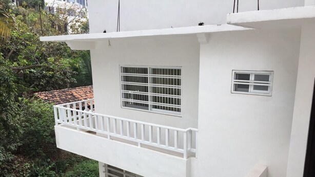 A white building with a balcony, a window, and a door.
