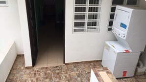 A laundry area with a washing machine, a small window, and a tiled floor.