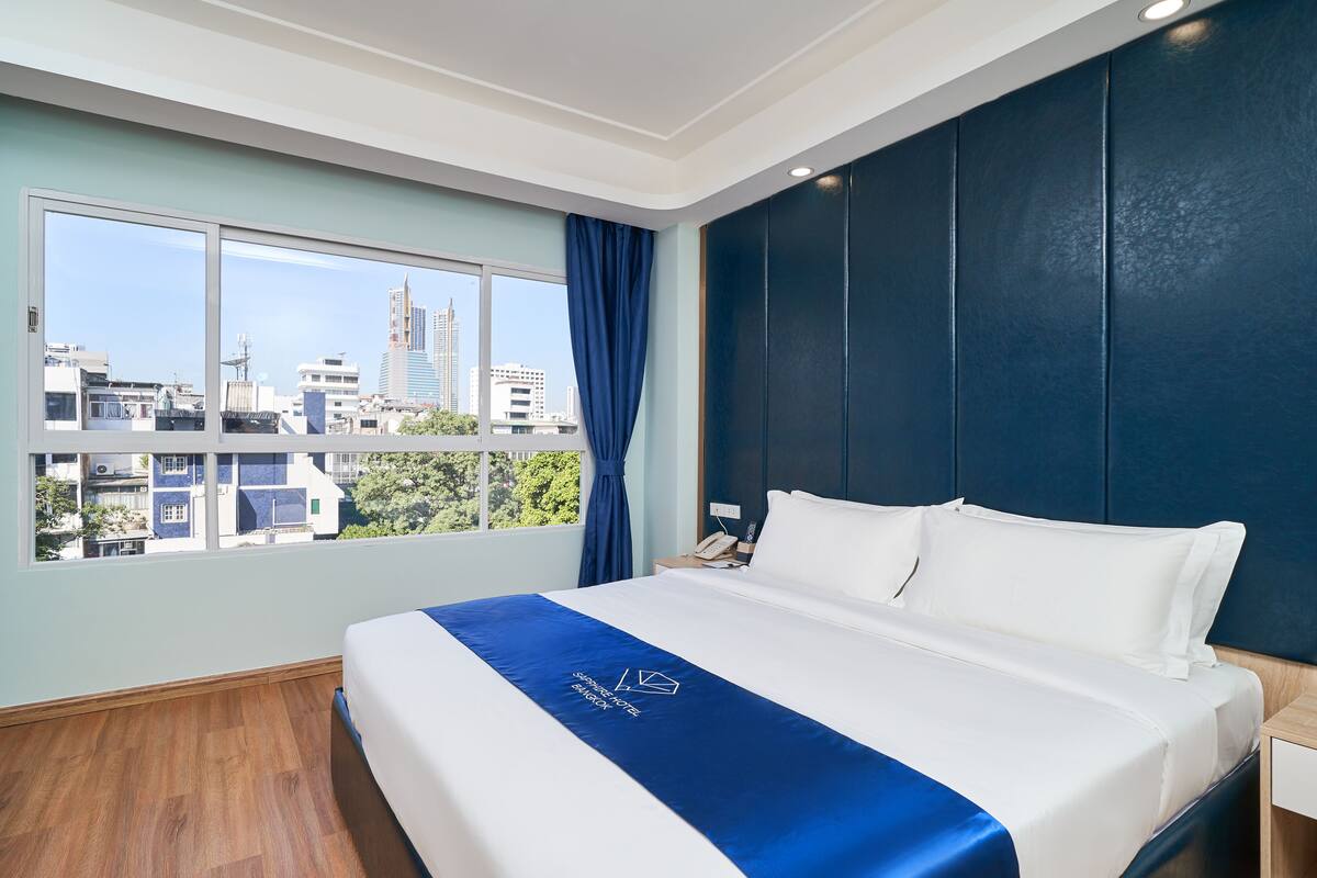 Une chambre d’hôtel avec un grand lit, une vue sur la ville et un mur d’accent bleu.