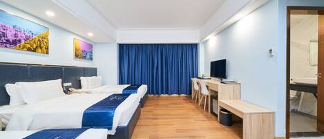 A hotel room with two beds, a desk, a chair, a TV, and a bathroom door.