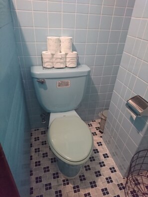 A bathroom with a toilet, blue tiles, and a patterned floor. - Kokusaburo House (Onna)