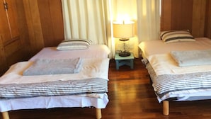 Dos camas individuales con almohadas y una mesita de noche con lámpara entre ellas.