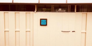 A beige building with a sign that reads "Entrance" in Japanese characters. - Kokusaburo House (Onna)