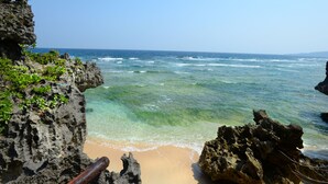 A coastal scene with clear turquoise water, rocky cliffs, and a sandy beach. - wisteria ocean Nakijin (Nakijin)