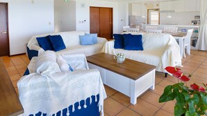 A modern hotel room with a living area, a dining table, and a kitchenette. - wisteria ocean Nakijin (Nakijin)