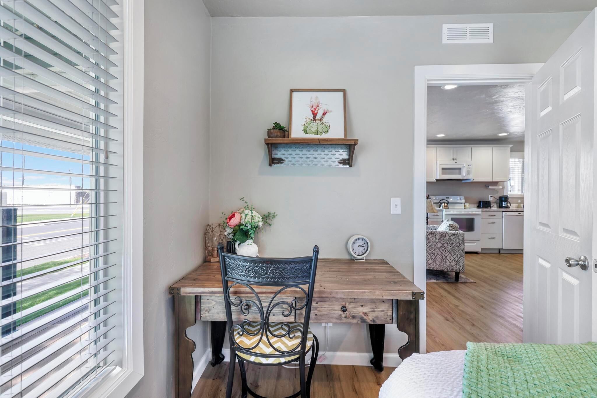 A compact kitchen with white cabinets, a microwave, and a dining area with a wooden table and metal chair.