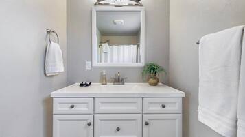 Un baño con tocador blanco, espejo y perchero.