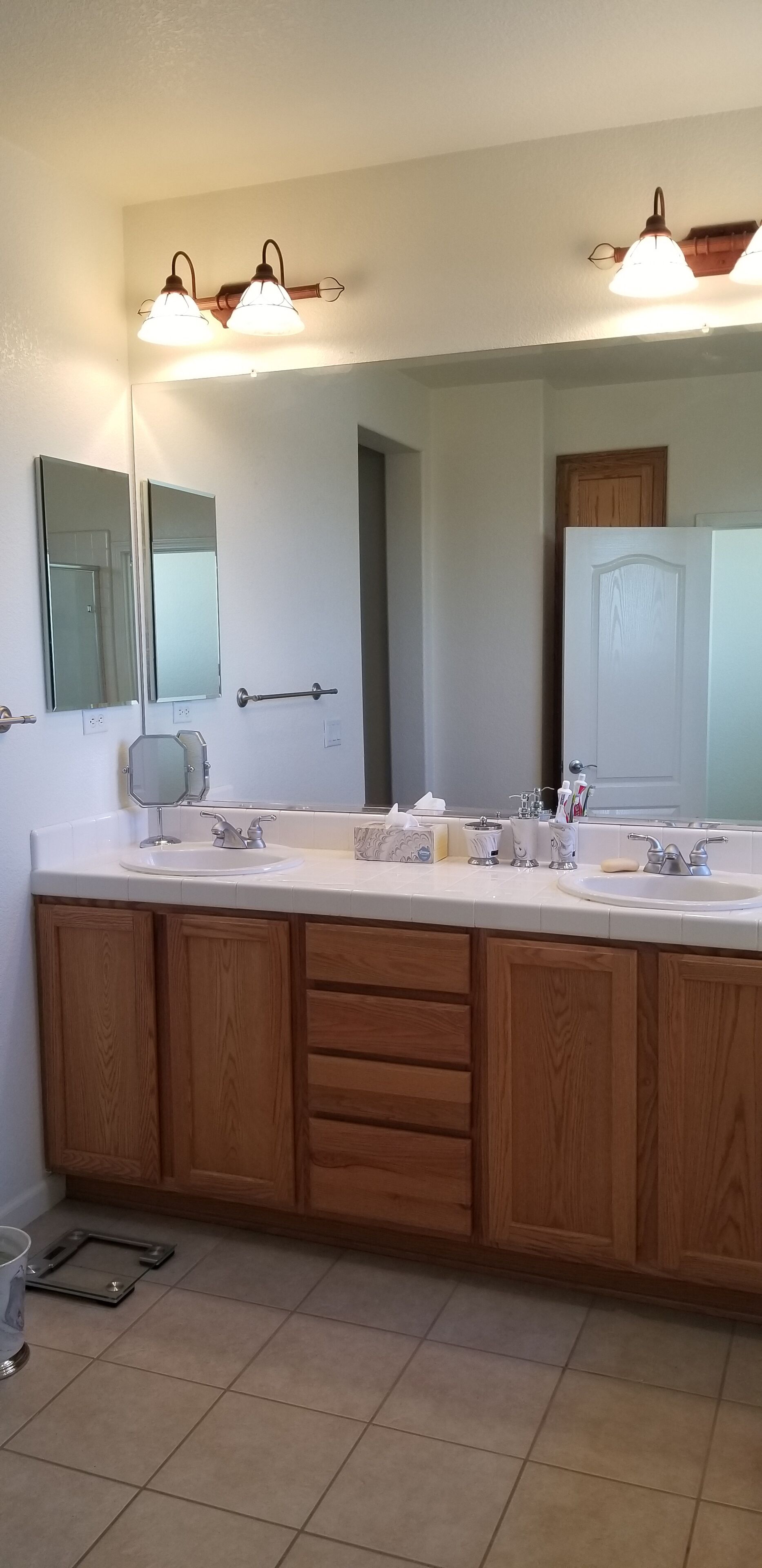 Une salle de bain dotée d’un grand meuble-lavabo, de deux éviers, d’un miroir et d’armoires en bois.