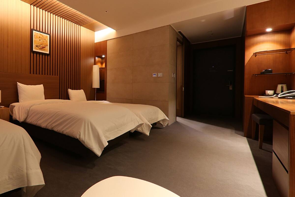 Habitación de hotel con dos camas, un escritorio y un baño.