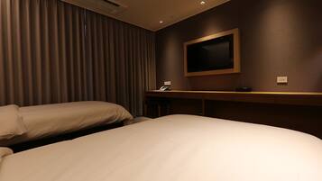 A hotel room with two beds, a flat-screen TV mounted on the wall, a desk with a telephone, and a minibar.