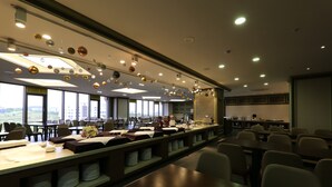 Una sala de conferencias moderna con mesas largas, sillas y una mesa de buffet.