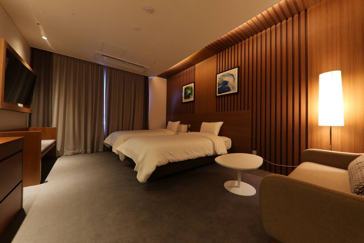 Una habitación de hotel con cama, escritorio, silla, televisor y lámpara.