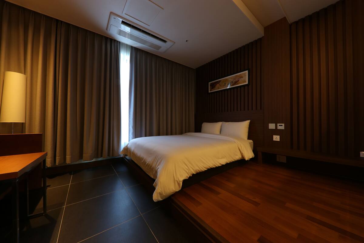 Habitación de hotel con una cama, un escritorio y una ventana con cortinas.