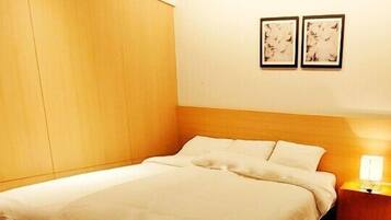 A hotel room with a bed, a nightstand with a lamp, and two framed pictures on the wall.