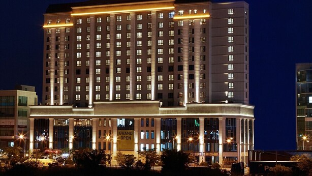 Un hotel de varios pisos con una entrada destacada y señalización iluminada.