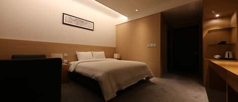 Habitación de hotel con cama, mesita de noche, lámpara y un cuadro en la pared.
