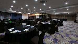 Un salón de conferencias con mesas redondas, sillas y una zona de escenario.