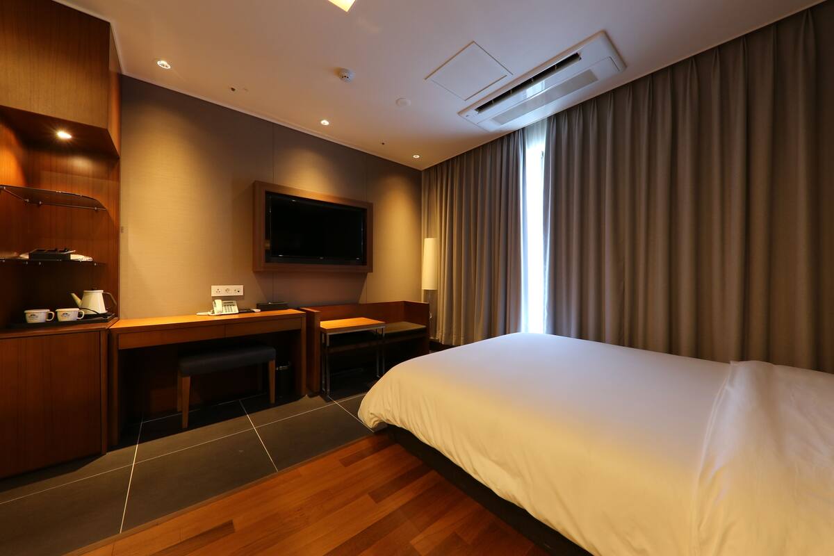 Habitación de hotel con cama, escritorio y televisor.