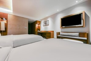 Een hotelkamer met twee bedden, een bureau, een stoel, een aan de muur bevestigde televisie en een fotolijst.